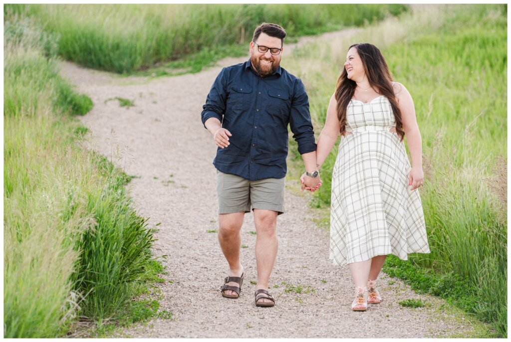 Dustin & Kristyn - Wascana Trails Engagement - 01 - Couple hold hands walking down the path