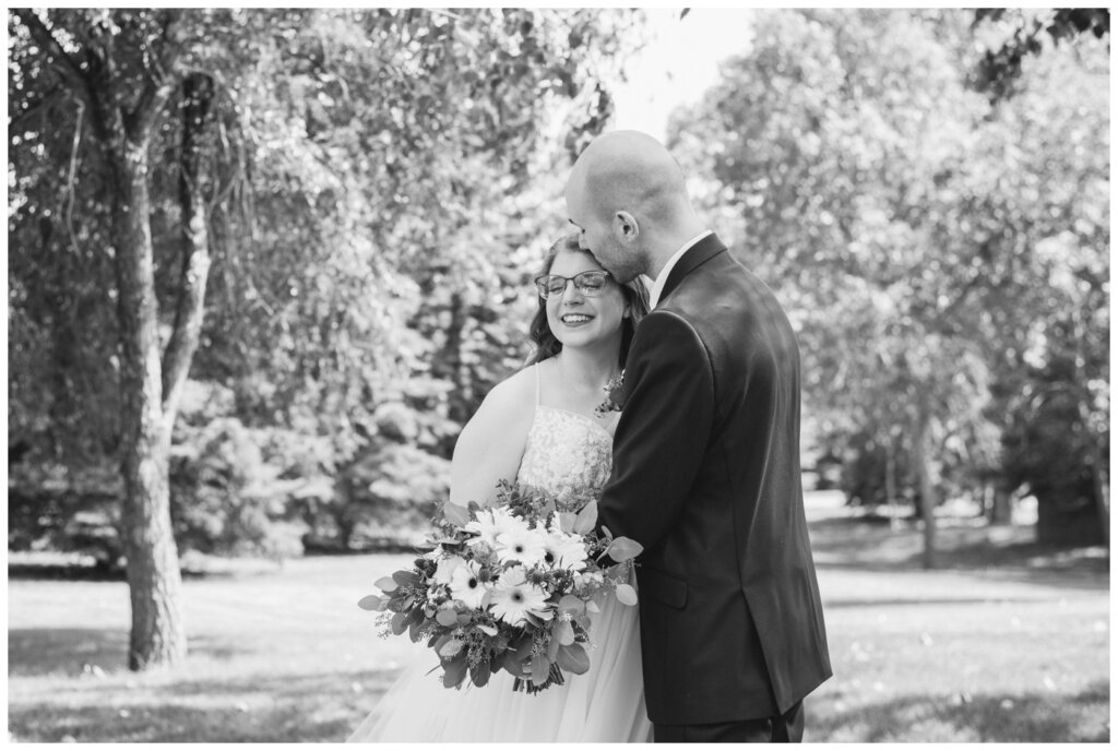 Evan & Melissa - Regina Wedding - Parkridge Park - 13 - Groom kisses bride on the temple