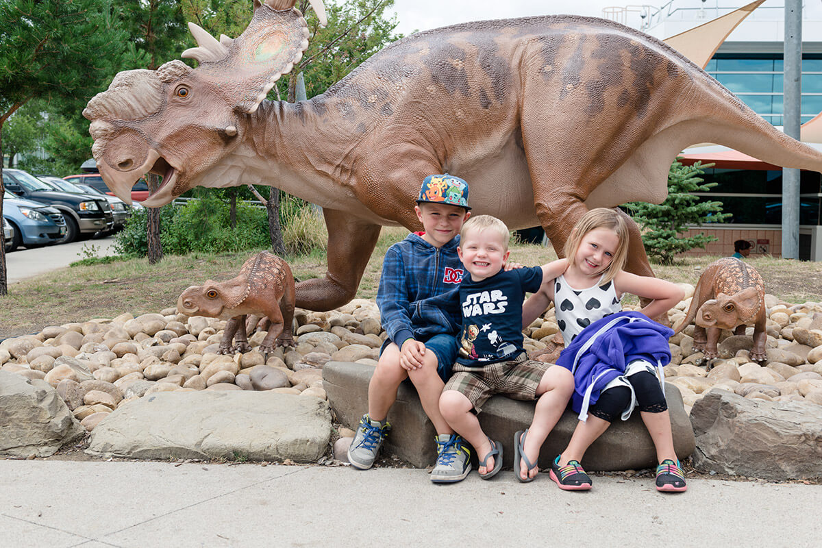 Liske kids with three dinosaurs at Drumheller Royal Tyrell Museum