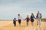 Family walking hand in hand in a harvested wheat field