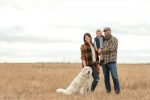 Family with their white dog in harvested field