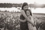 Sisters hugging together at sunset in black and white
