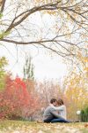 Couple sitting on the grass in fall surrounded by leaves