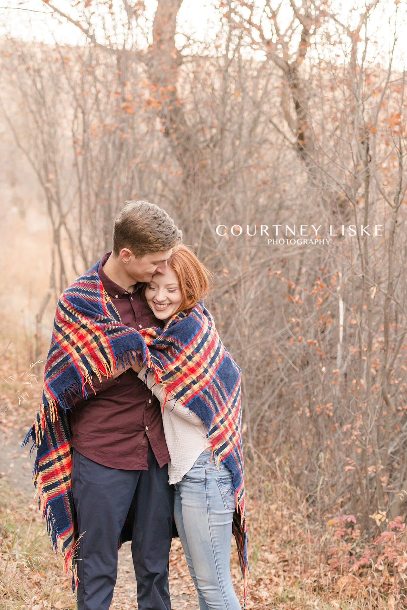 Couple snuggling under a blue and red plaid blanket