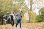 Couple walking through Wascana Park holding hands