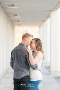 Engaged couple stands amongst white pillars