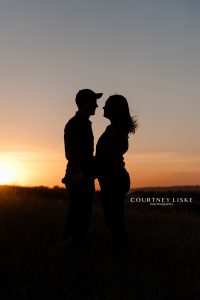 Man and woman standing in field at sunset