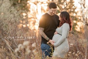 Couple stand together at sunset for their maternity session with Courtney Liske Photography