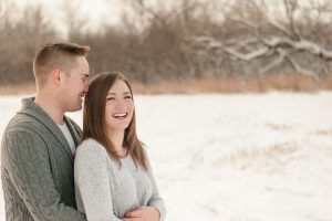 Man in grey sweater holds his fiancee in her white sweater