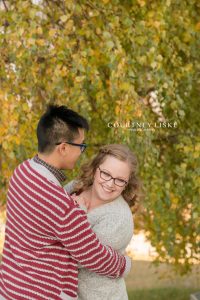 Man in red and white sweater snuggling with his fiancee