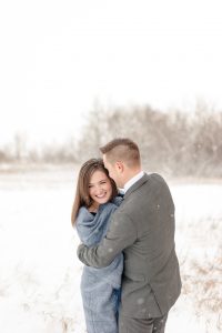 Woman wrapped in blue blanket with her fiancee in grey suit in the snow