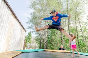 Boy in Superman sweater jumps on a trampoline