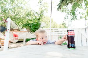 Little boy drinking glass bottle Coca-Cola