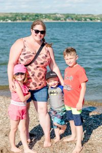 Woman in pineapple tank top with three children at the beach