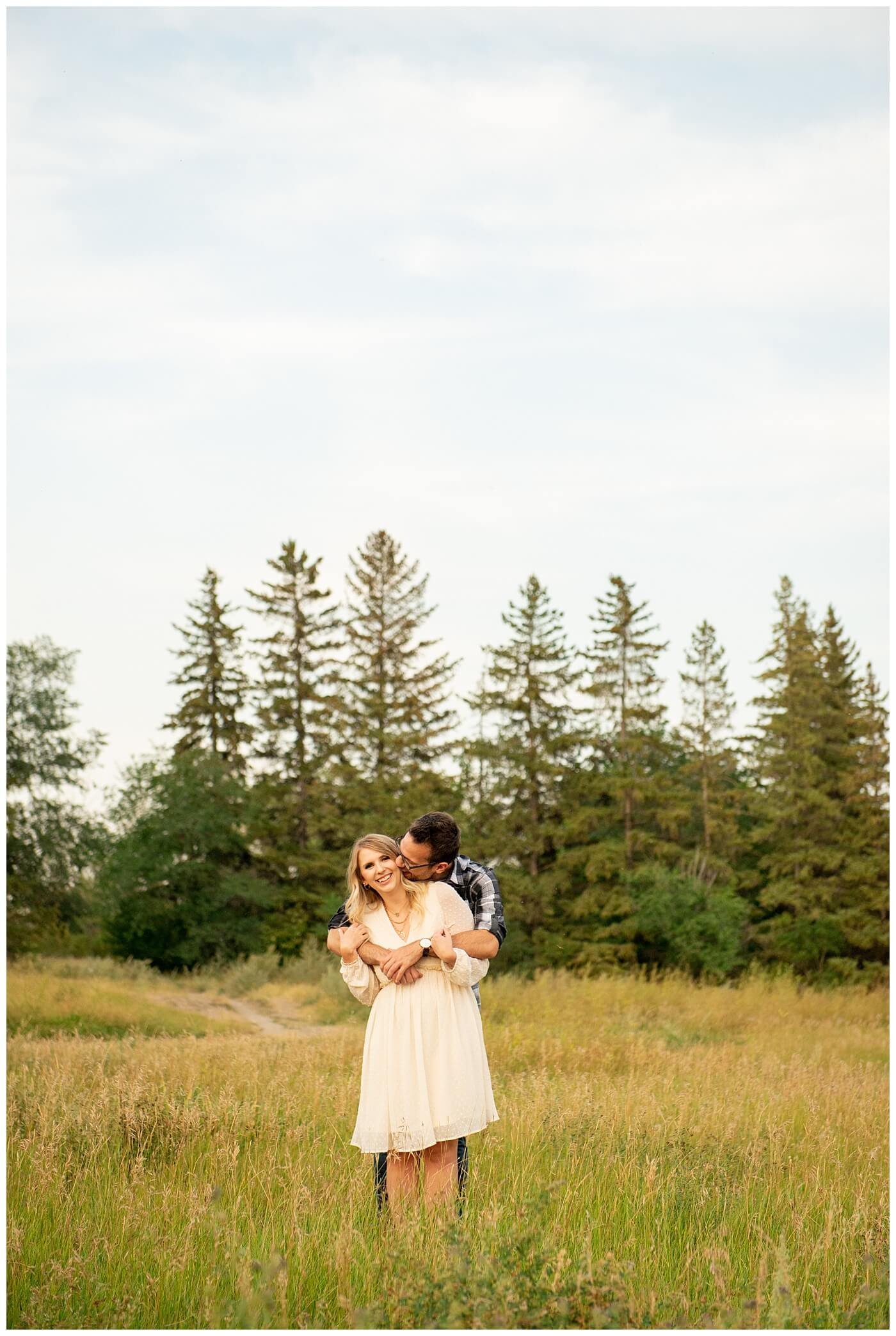 Regina Engagement Photography with Brett & Rachelle. Natural Light Engagement Session in Douglas Park. Regina Couple snuggle in a field of tall grass outside the Wascana Habitat Conservation Area