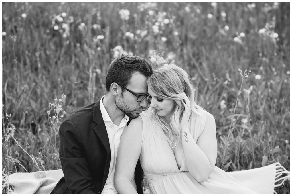 Regina Wedding Photographer - Natural Light Engagement Session in Douglas Park Regina - Couple sit on a blanket in tall grass at sunset