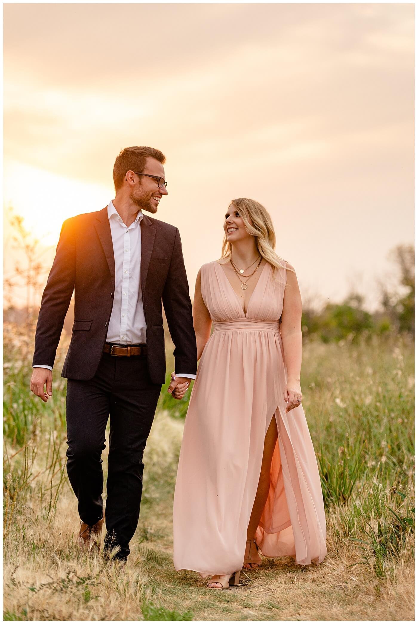 Regina Wedding Photographer - Natural Light Engagement Session in Douglas Park Regina - Couple walk along the path at sunset inside the Wascana Habitat Conservation Area