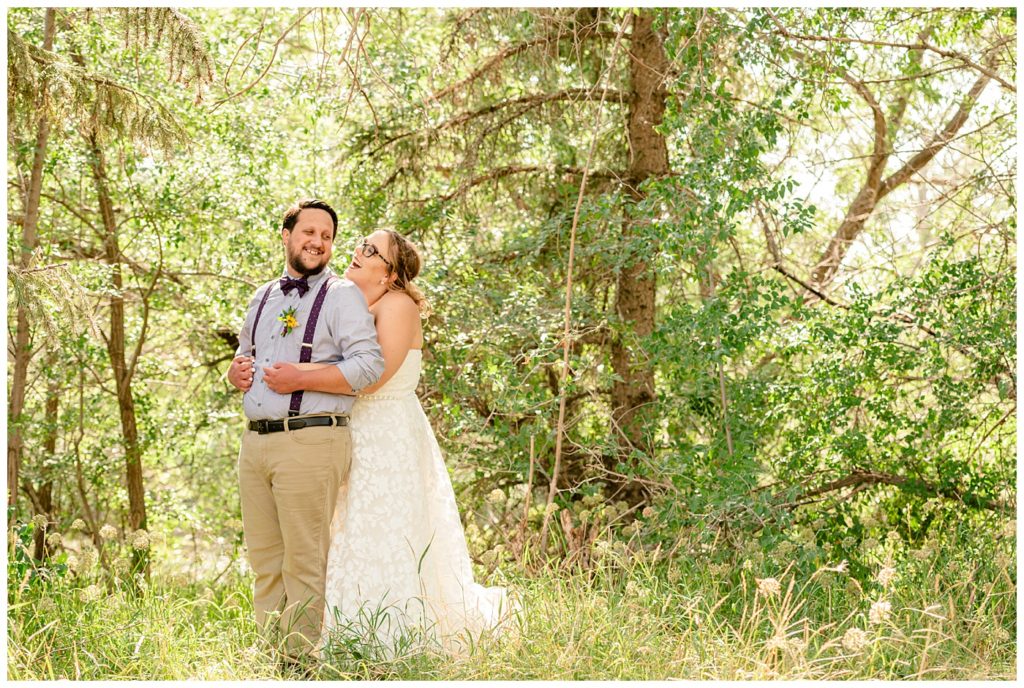 Regina Wedding Photographers - Ryan - Aeliesha - Bride stands behind her groom amongst the trees