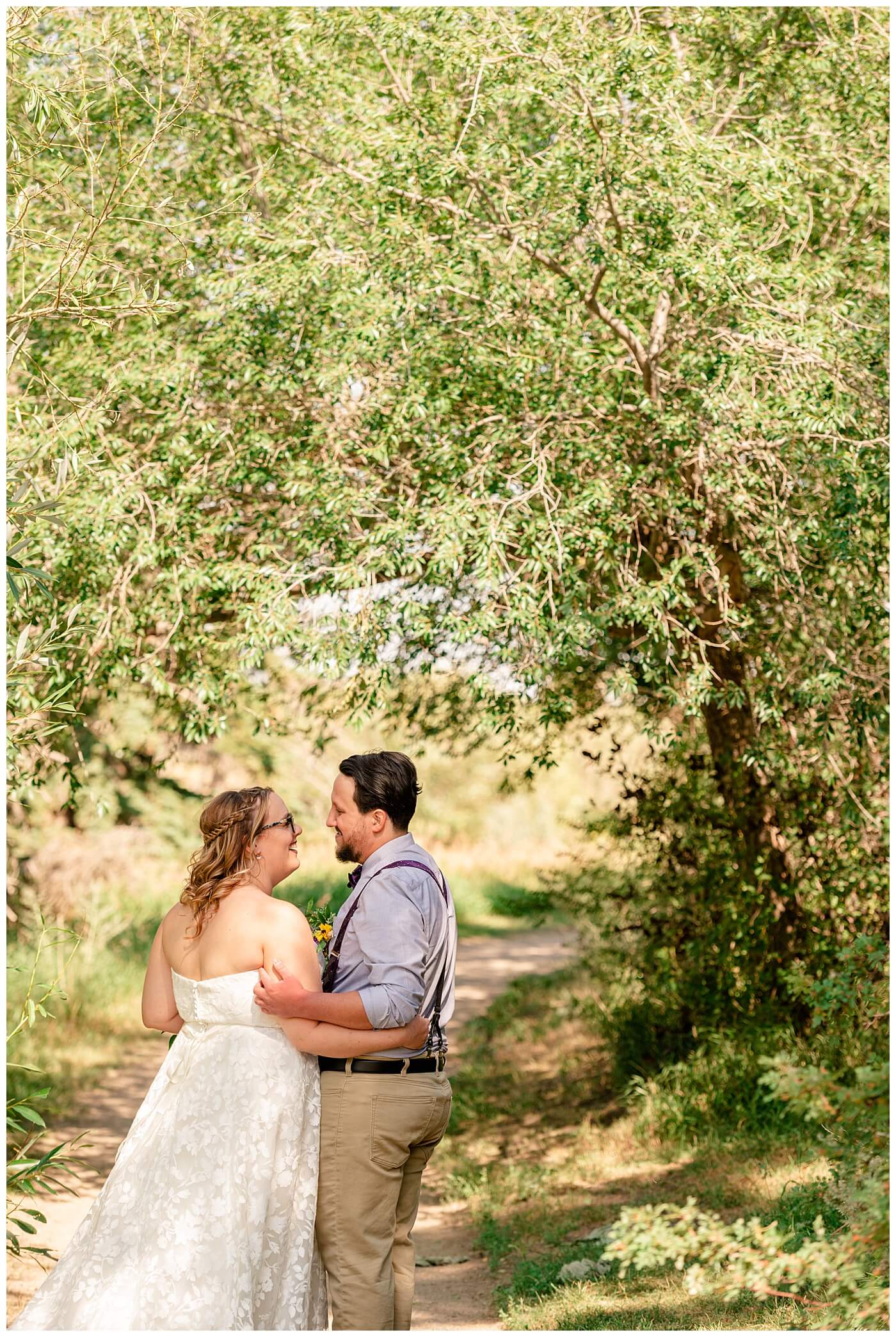 Regina Wedding Photography - Ryan - Aeliesha - Bride & Groom stand under an archway of trees on the island in AE Wilson Park.jpg