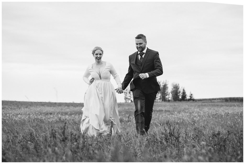 Regina Wedding Photography - Tyrel - Allison - Bride & Groom run through the field hand in hand