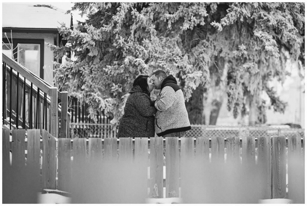 Regina Family Photography - Ashley - Scott - Couple share a kiss in the snow in their front yard