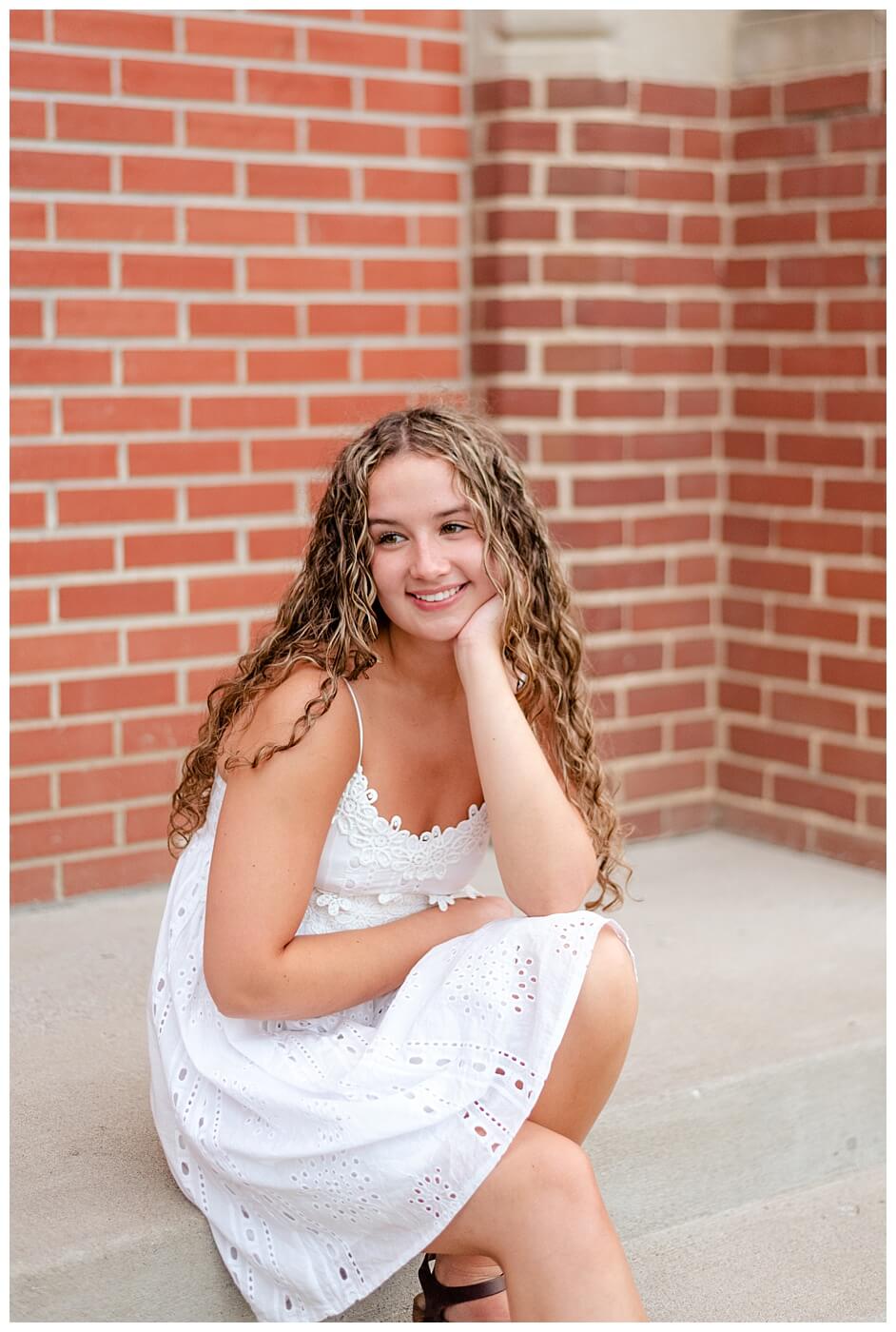 Cailey Baseden - Graduation 2021 - 11 - Grad sitting on steps in white dress