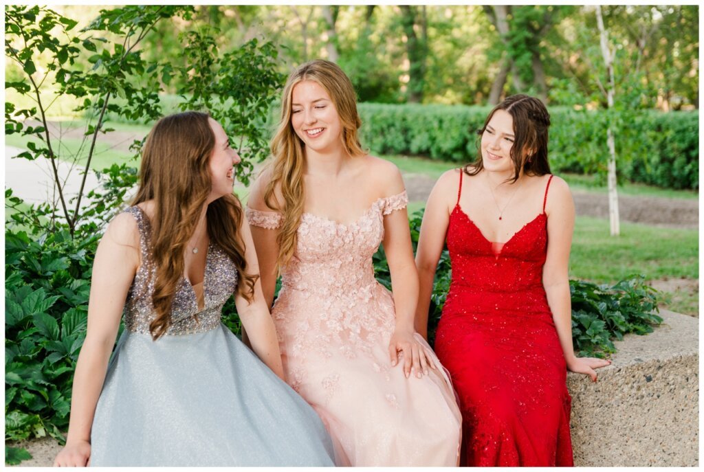 Graduate girls sit together on stone wall