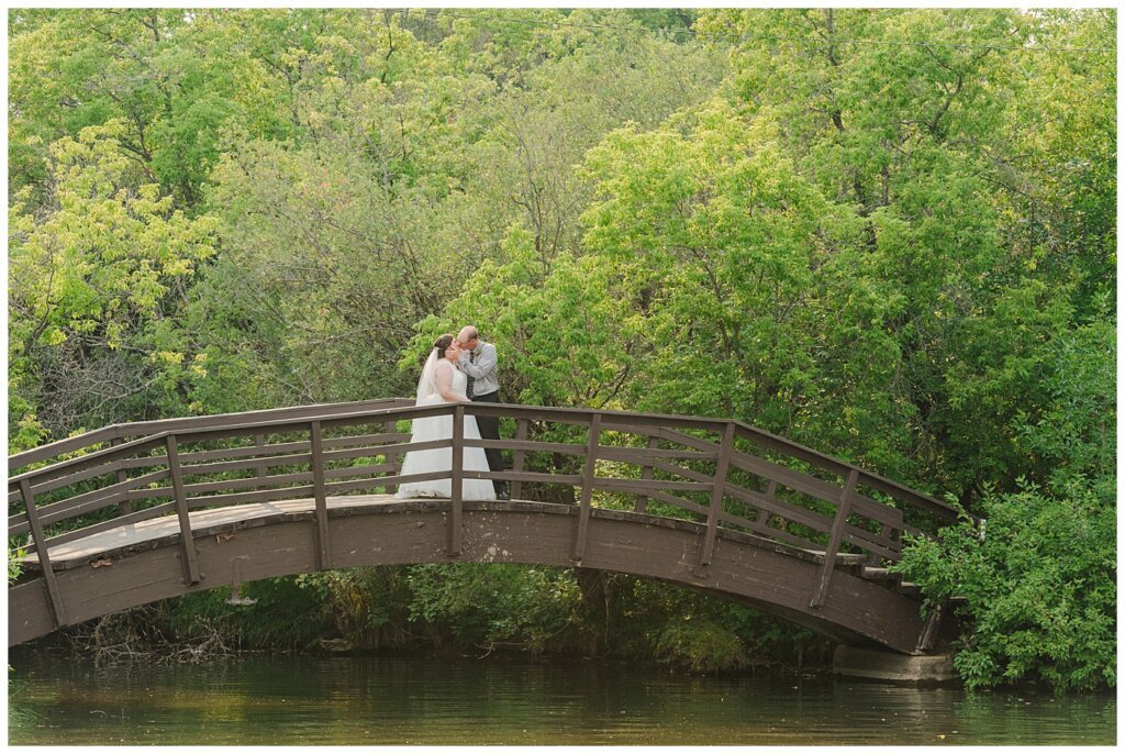 Sheldon & Amy - Besant Campground Wedding - 20 - Couple share a kiss on the bridge