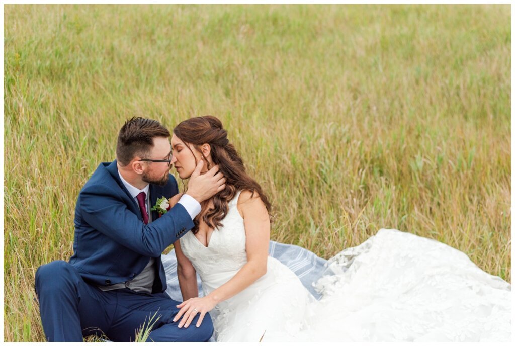 Andrew & Lacey - 39 - Bride & groom sitting in a field kissing