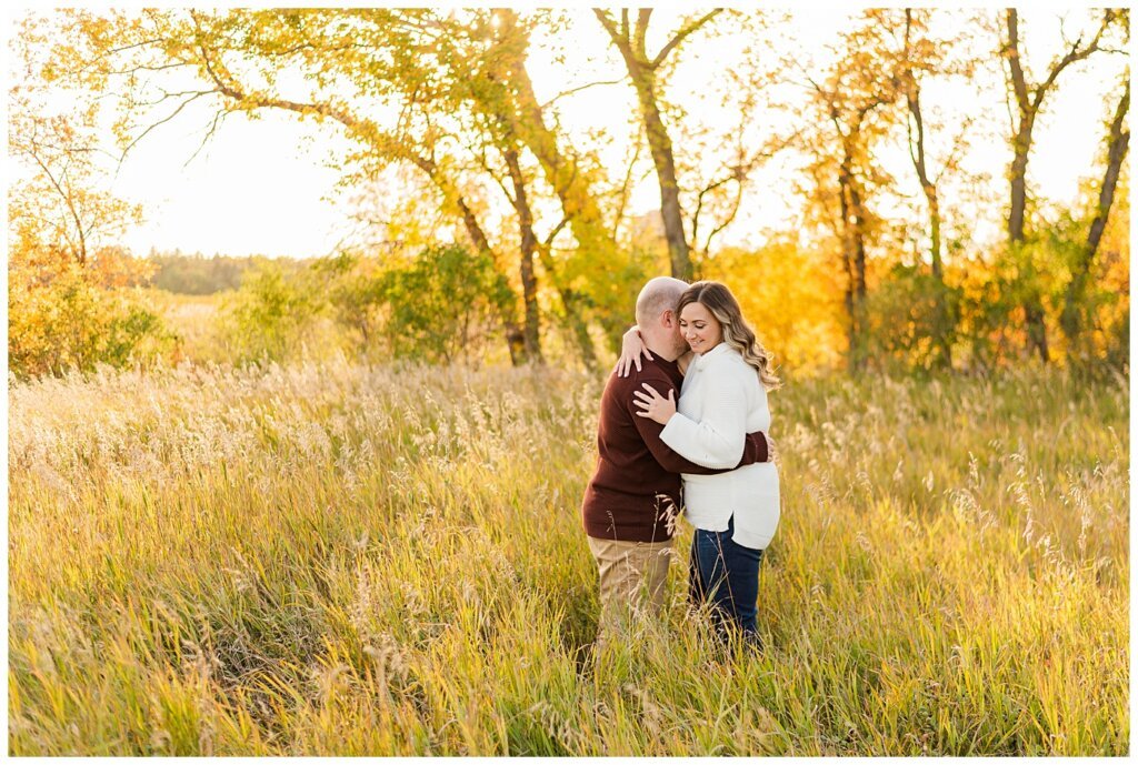 Trevor & Kim - Regina Engagement Session - Wascana Centre Habitat Conservation Area - 05 - Nuzzle into neck in open field in Saskatchewan