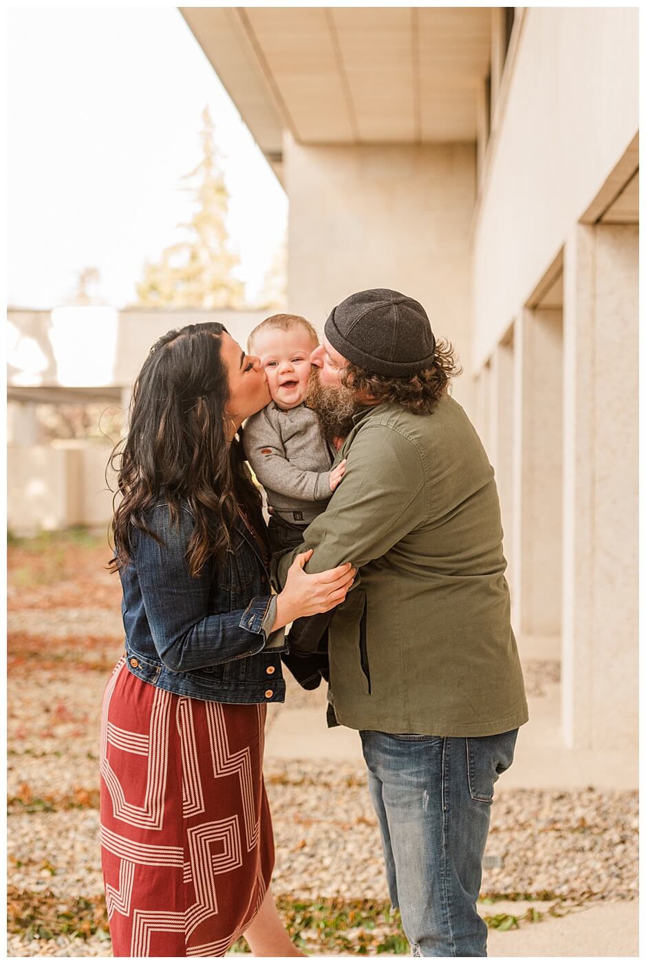 Regina Family Photographers - Keen Family - 2021 - TC Douglas Building - 05 - Father and mother kissing toddler's cheeks