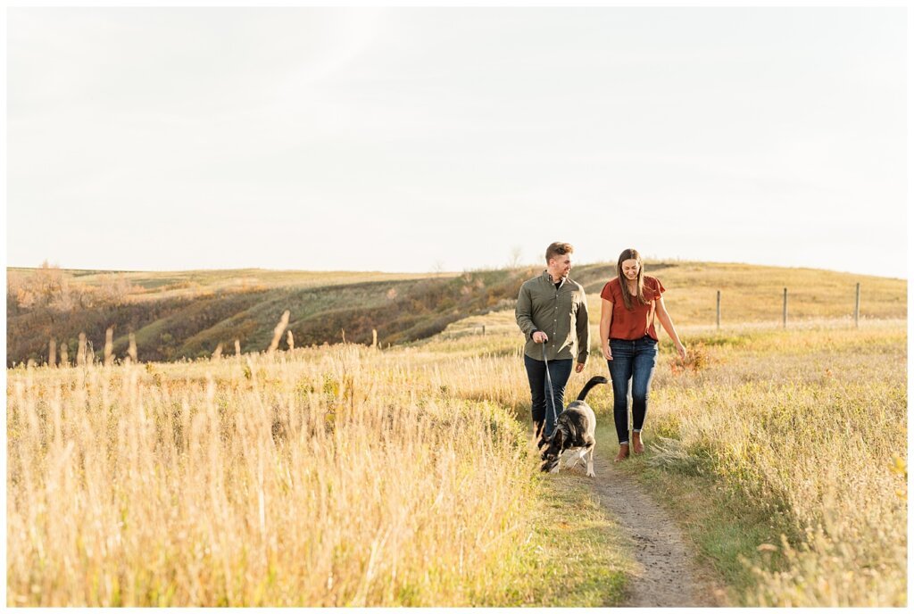 Tris & Jana - Engagement Session - Wascana Trails - 01 - Couple walking with Dog on trail