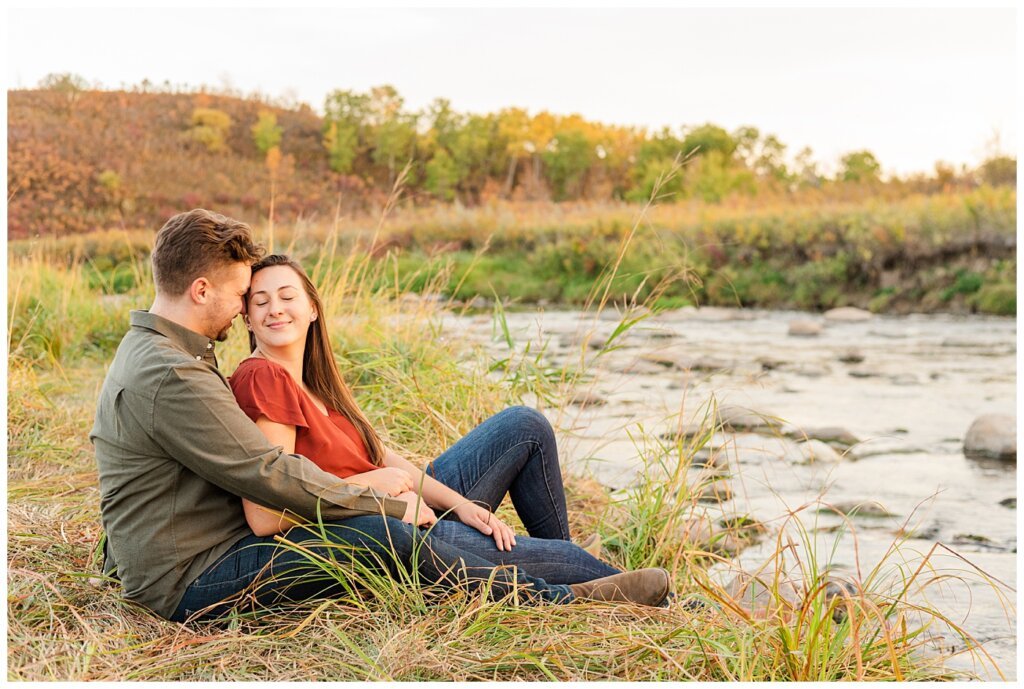 Tris & Jana - Engagement Session - Wascana Trails - 11 - Sitting by Wascana Creek