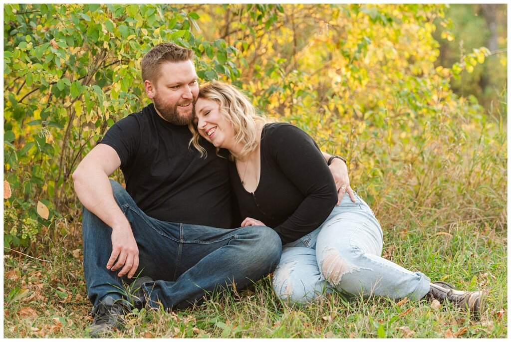 Tyrel & Allison - Regina Anniversary Session - Douglas Park Hill - 01 - Couple laughing as they sit on the grass