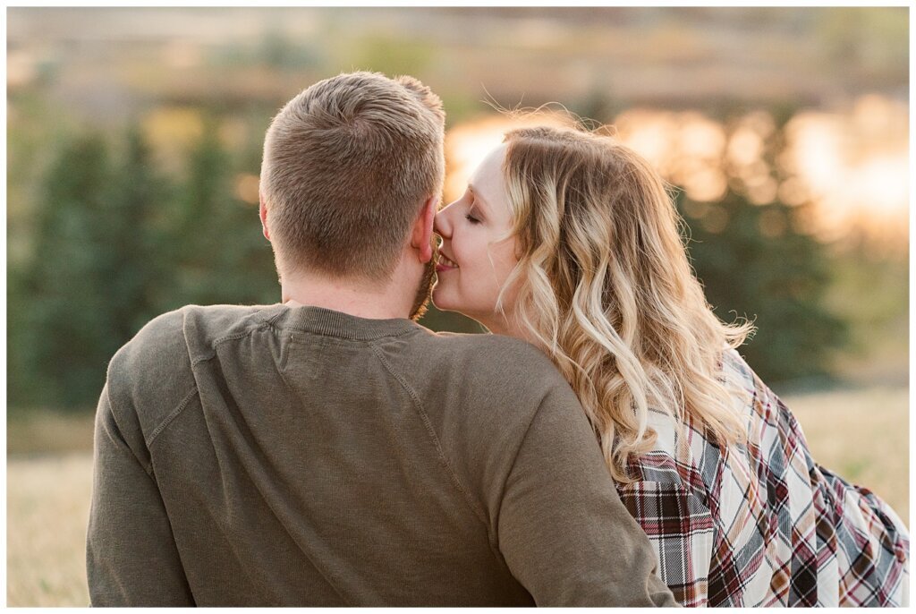 Tyrel & Allison - Regina Anniversary Session - Douglas Park Hill - 08 - Wife whispering into husbands ear as they watch sunset on hilltop