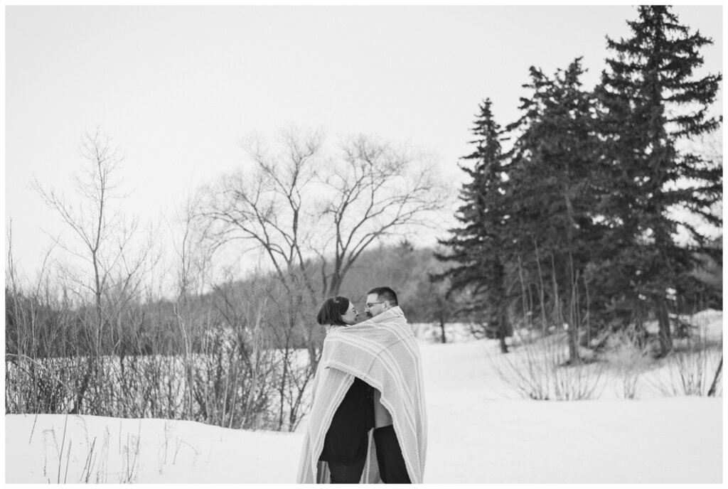 Black and white photo of couple cuddling under blanket in Regina at Science Centre.