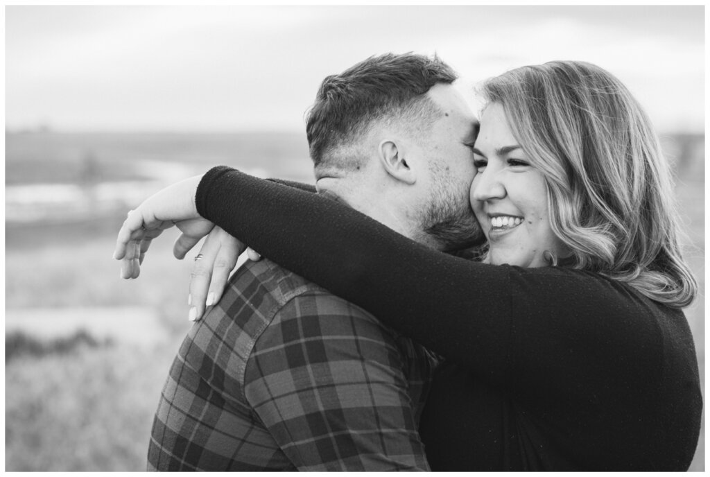 Black and white image of fiance leaning in to whisper in fiancee's ear