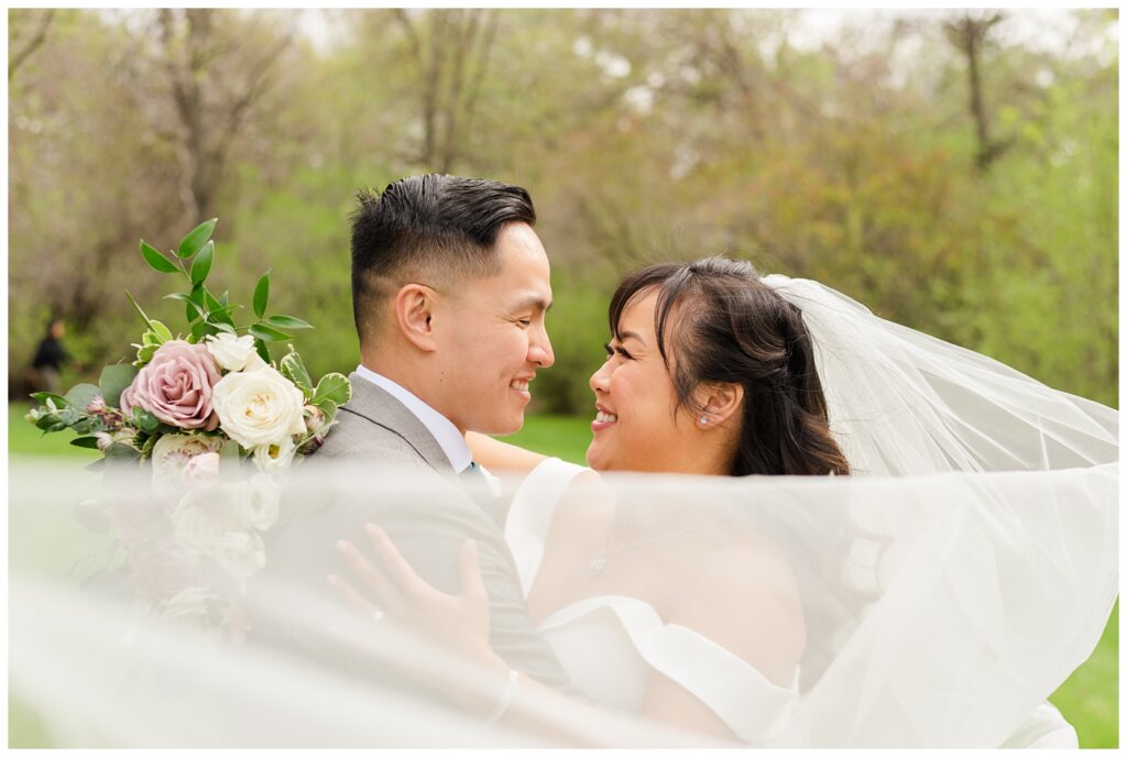 Sam & Benton - Wascana Park - 30 - Bride & groom behind cathedral length veil