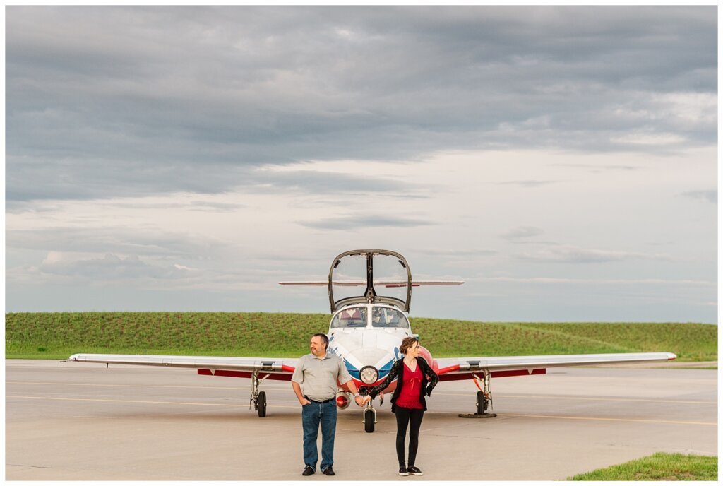 Shawn & Jennifer - 15 Wing Moose Jaw - 04 - Couple hold hands in front of Snowbird Military Aerobatics Flight Demonstration Team plane