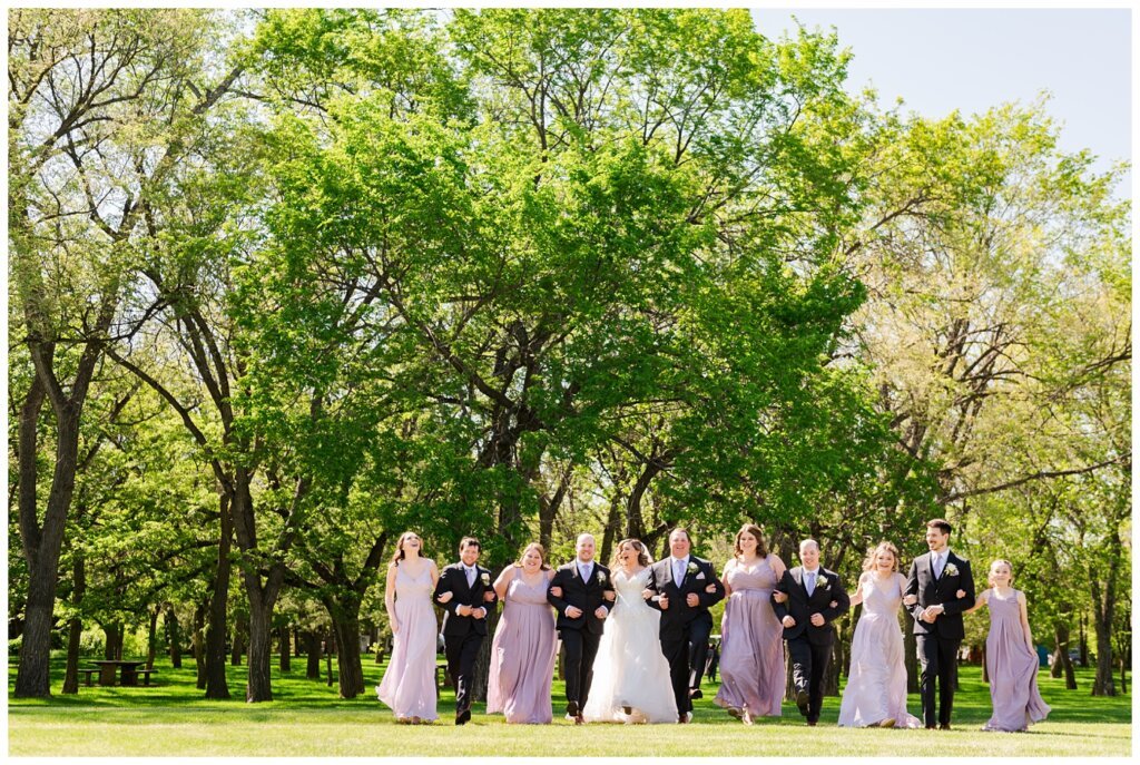 Trevor & Kim Wedding - 25 - Royal Saskatchewan Museum - Wedding party wizard of ozzing through the park