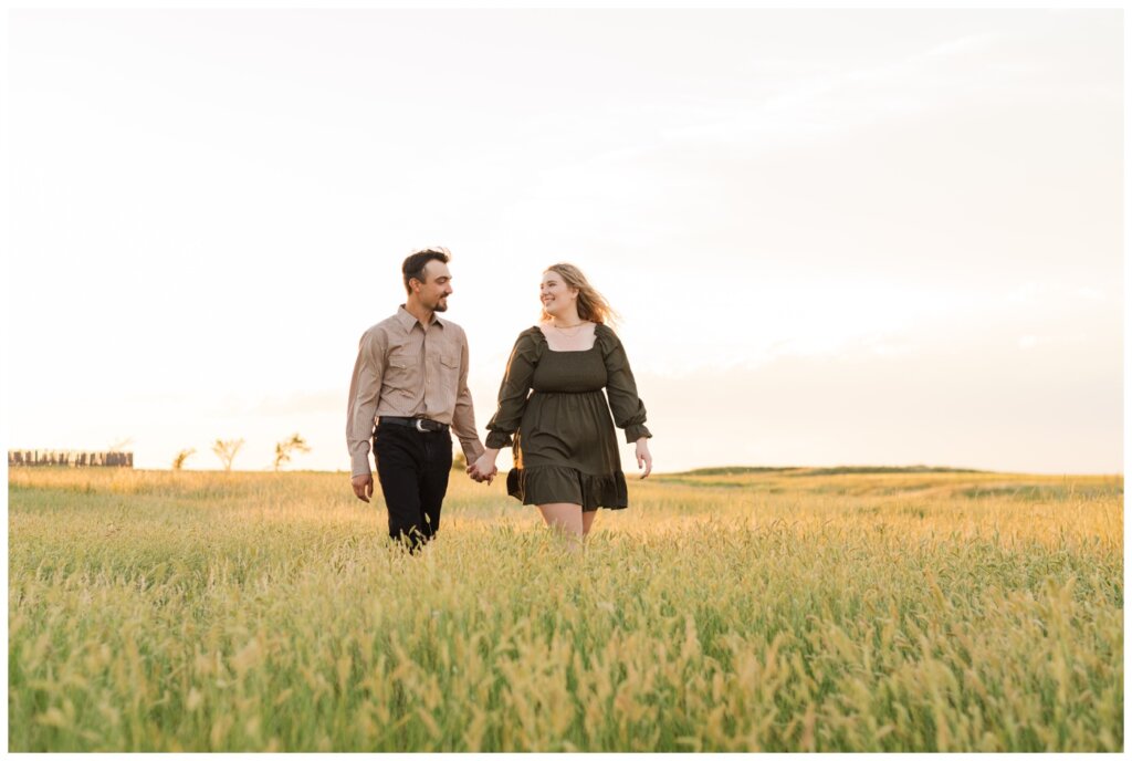 Orrin & Jade - 10 - Weyburn Engagement - Couple walks through field of grass