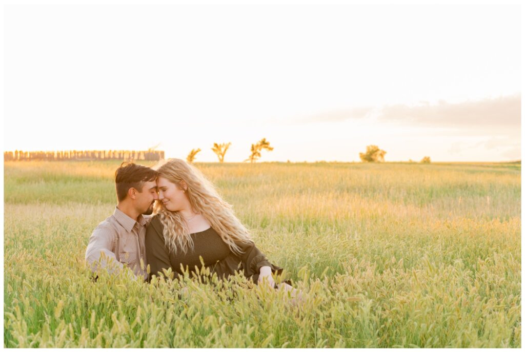 Orrin & Jade - 11 - Weyburn Engagement - Couple sits in field of grass
