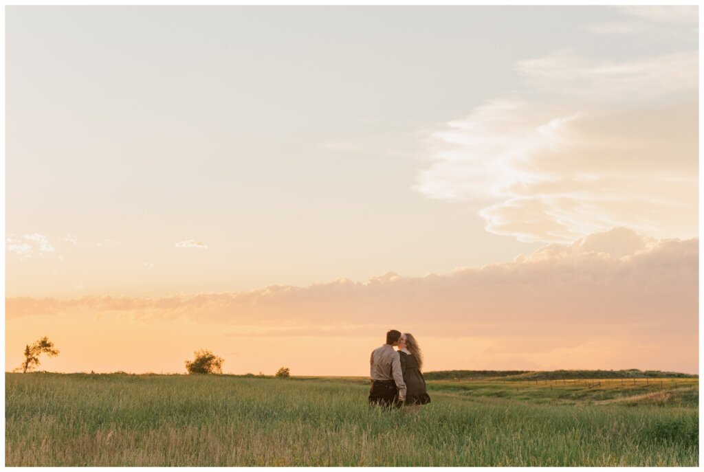 Orrin & Jade - 14 - Weyburn Engagement - Couple walks through field of grass