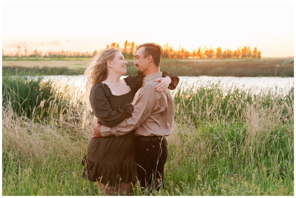 Orrin & Jade - 15 - Weyburn Engagement - Couple embrace overlooking the water