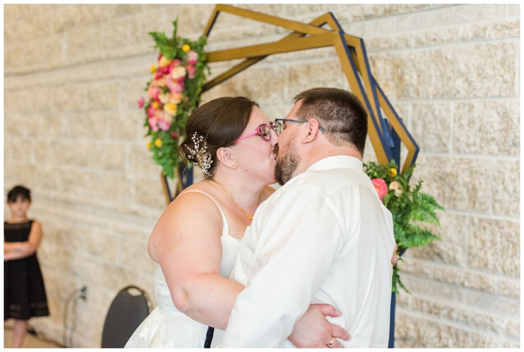 Paul & Lubomyra - Ukrainian Wedding - 33 - Bride & Groom kissing in front of custom backdrop at reception