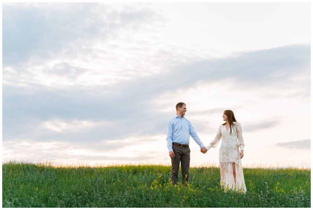 Ryan & Melissa - 16 - Wascana Habitat Conservation Area - Couple holds hands on side of hill