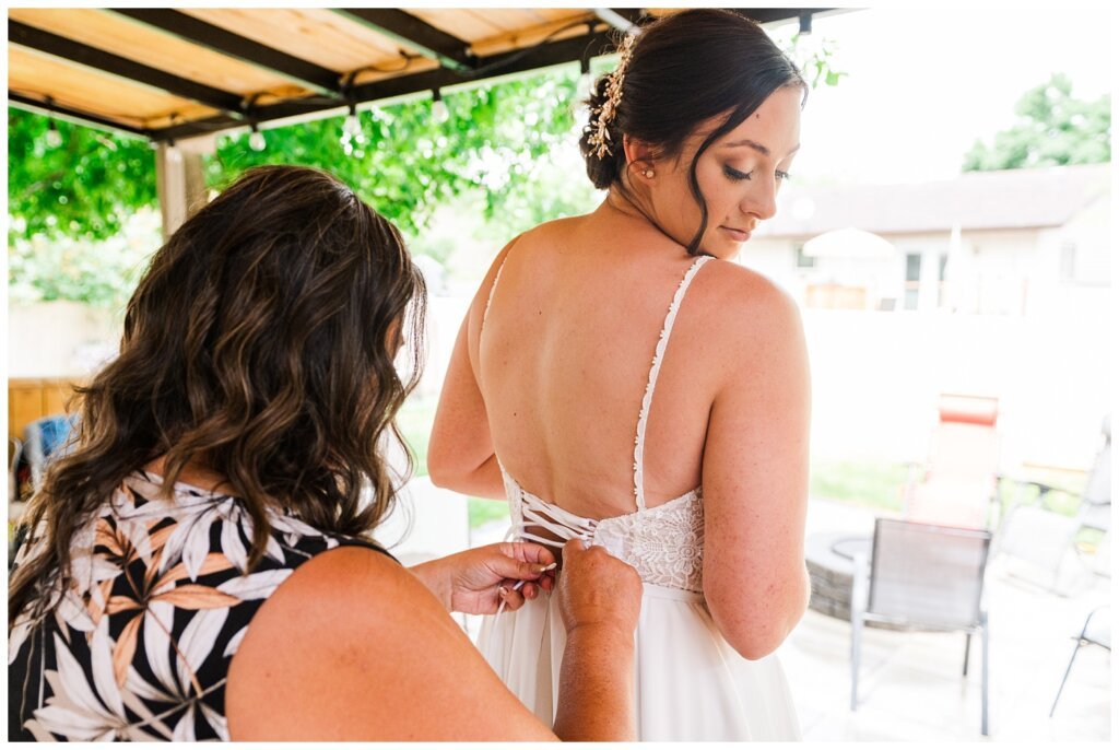 Tris & Jana - Lumsden Wedding - 11 - Bride has help doing up her dress by her mom