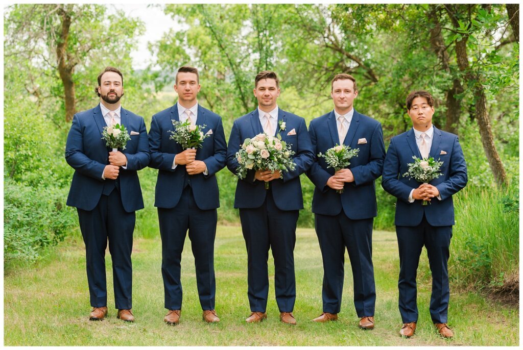 Tris & Jana - Lumsden Wedding - 24 - Groom & groomsmen pose with flowers from The Flower Hut Regina