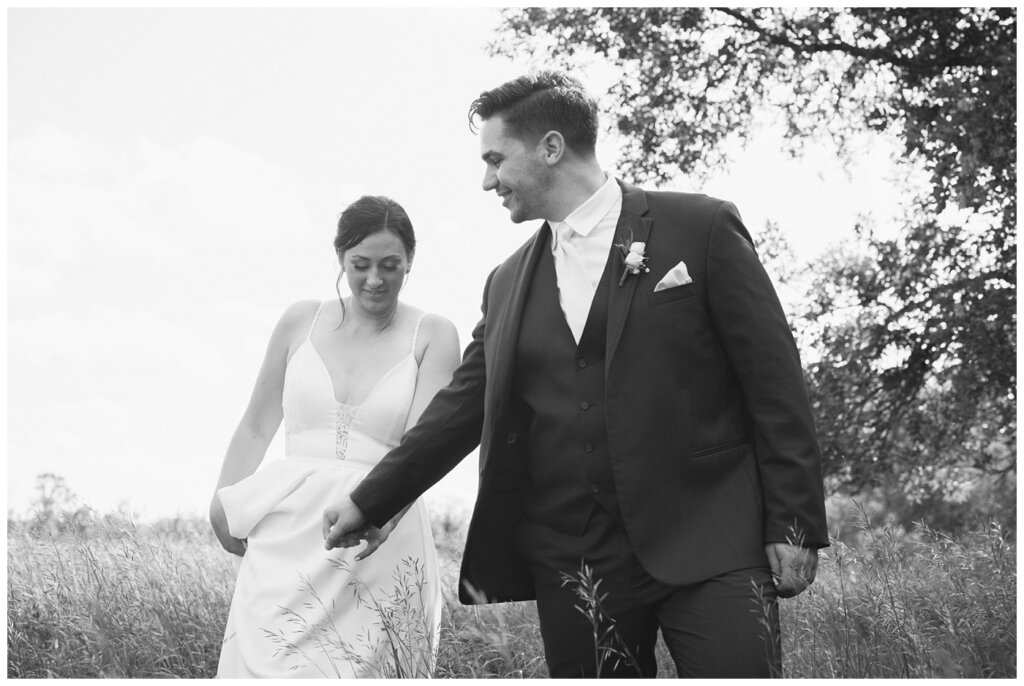 Tris & Jana - Lumsden Wedding - 28 - Groom leads his bride through tall grass