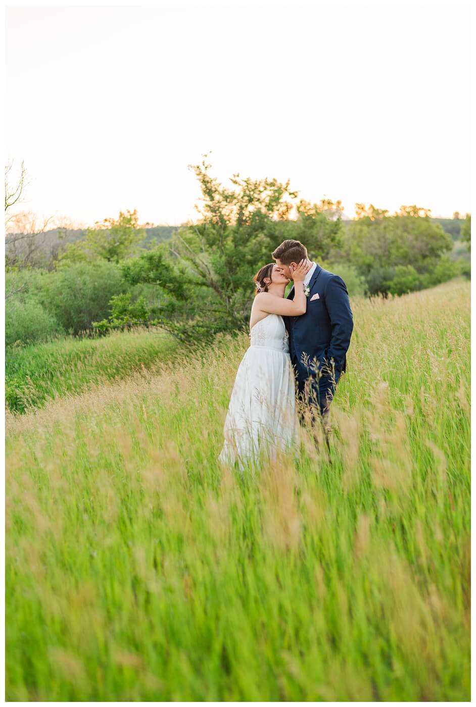 Tris & Jana - Lumsden Wedding - 40 - Bride & Groom stand in tall grass near Lumsden